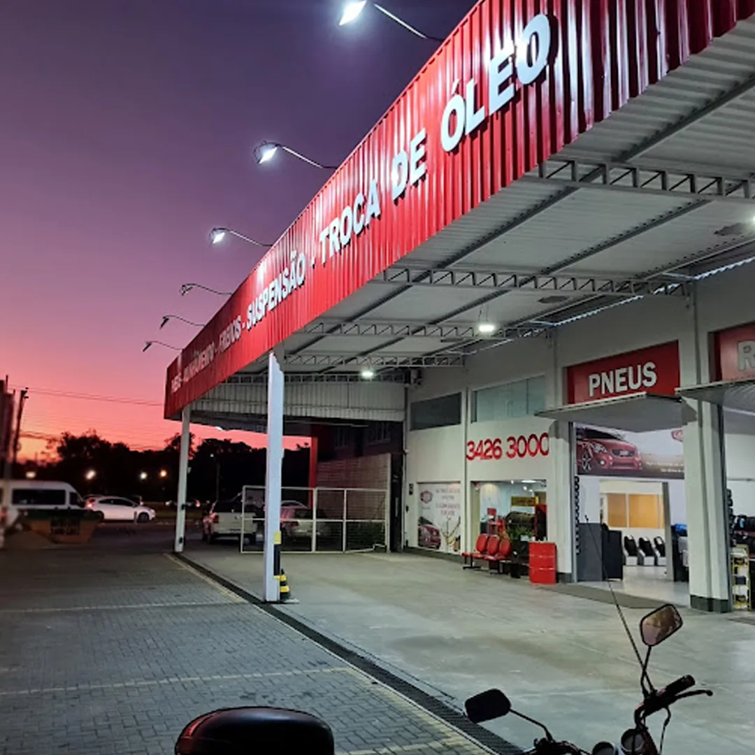 Fachada da Ande Pneus & Auto Center em Joinville ao entardecer, com o letreiro aceso